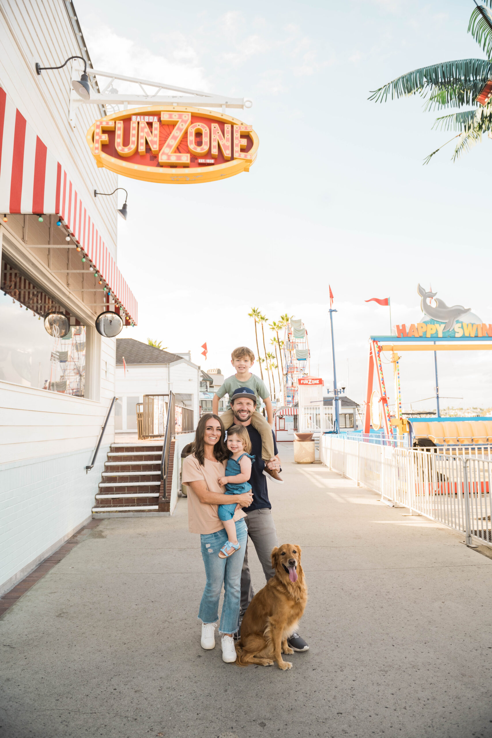 Family portrait with golden retriever in front of an outdoor FunZone, summer lifestyle session